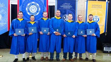 Baseball graduates holding diplomas in their regalia