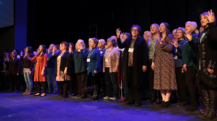 Alumni on the McDonald Moody Auditorium stage singing the alma mater