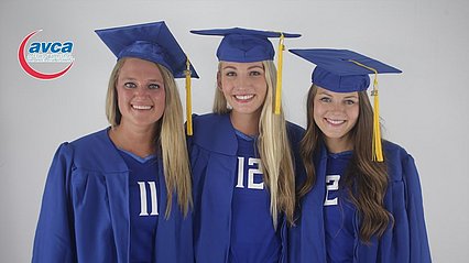 Volleyball players pose in graduation regalia. 