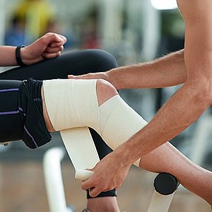 athletic trainer wrapping athlete's leg