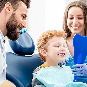 dentist showing a child their teeth in a mirror