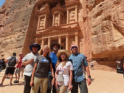 A group of five individuals standing together and posing in front of Al-Khazneh in Petra, Jordan