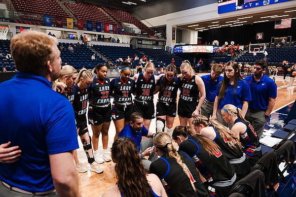 the team huddles around Coach Gomez during a timeout late in the game