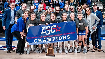 Lady chaps basketball team posing with banner