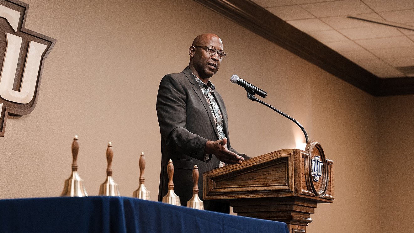 Speaker Jimmy Moore at the podium with the education award bells