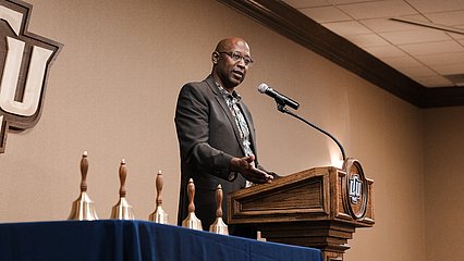 Speaker Jimmy Moore at the podium with the education award bells