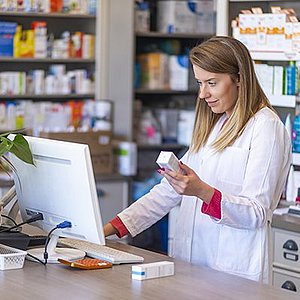 pharmacist checking some medication and looking at a computer