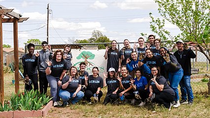 LCU Students giving the chaparral hand sign at one of the work sites with greenery