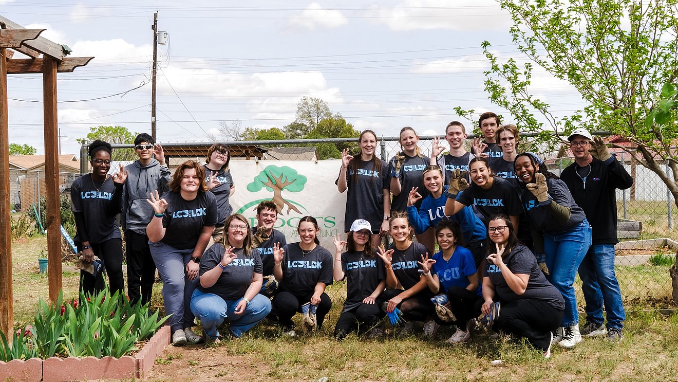 LCU Students giving the chaparral hand sign at one of the work sites with greenery