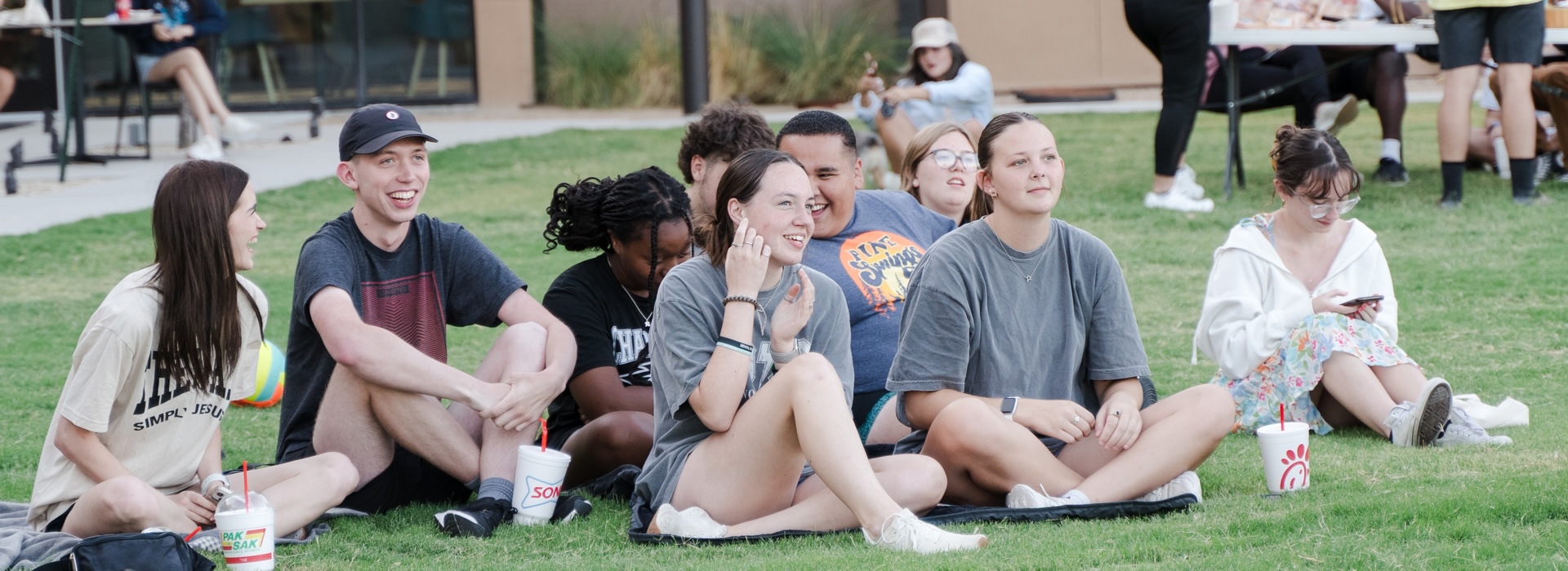 Photograph of students sitting on the lawn of one of LCU's residence halls