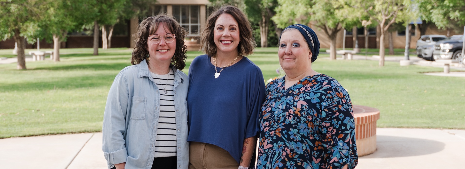 Photograph with Jessica, Natasha, and Jenny standing in front of the Welcome Center lawn
