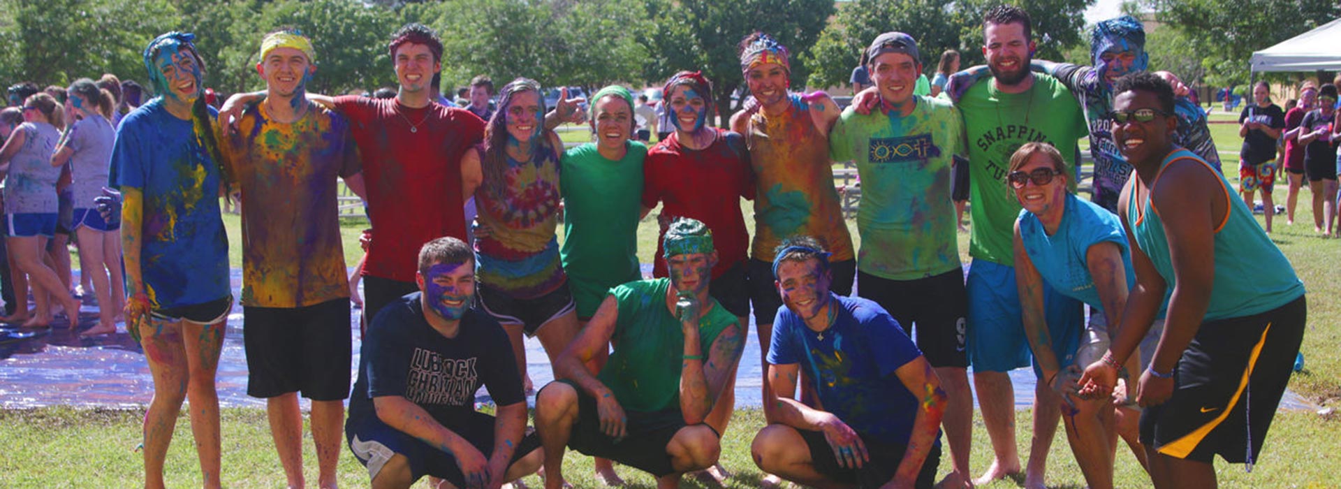 15 students posing for a group photo covered in paint